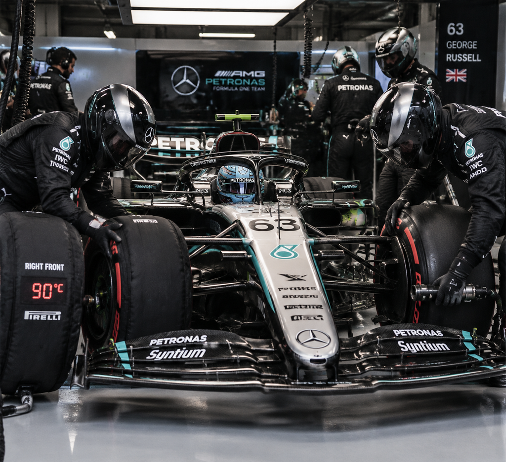 Kru mekanik Mercedes memasang ban kompon lunak Pirelli pada mobil George Russell di garasi pit lane.